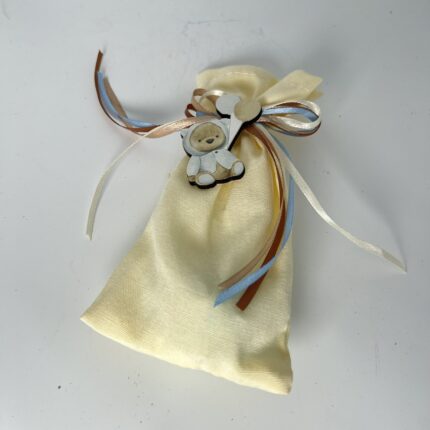 Αυτή η χειροποίητη μπομπονιέρα βάπτισης για αγόρι, φτιαγμένη από απαλό κίτρινο ύφασμα, είναι ένα τρυφερό δώρο για τους καλεσμένους. Οι σατέν κορδέλες, σε γαλάζιες, καφέ και λευκές αποχρώσεις, προσθέτουν μια παιχνιδιάρικη πινελιά, ενώ το ξύλινο αρκουδάκι, σκαλισμένο με λεπτομέρεια, συμβολίζει την αγάπη και τη φροντίδα προς το νεογέννητο αγοράκι. Το πουγκί, γεμάτο με κουφέτα και μικρά δωράκια, είναι ιδανικό για να ευχαριστήσει τους καλεσμένους και να τους χαρίσει ένα γλυκό ενθύμιο από αυτή τη σημαντική μέρα.