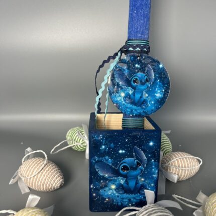 Αυτή η χειροποίητη πασχαλινή λαμπάδα με μολυβοθήκη είναι το ιδανικό δώρο για κάθε παιδί που αγαπά τον Stitch. Η λαμπάδα και η μολυβοθήκη είναι διακοσμημένες με τον Stitch, σε ένα μαγευτικό σκηνικό με αστραφτερά αστέρια. Η μολυβοθήκη μπορεί να χρησιμοποιηθεί και μετά το Πάσχα, για να οργανώσει τα μολύβια και τα χρώματα του παιδιού. Τα πασχαλινά αυγά που την πλαισιώνουν, προσθέτουν μια γιορτινή και παιχνιδιάρικη πινελιά. Είναι ένα δώρο που θα αγαπηθεί και θα γίνει το αγαπημένο των μικρών φίλων του Stitch!