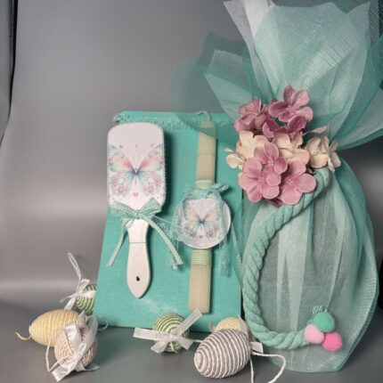 Αυτό το χειροποίητο πασχαλινό δώρο αποτελείται από μια λαμπάδα και μια χτένα μαλλιών, αφιερωμένο στην ομορφιά της πεταλούδας. Η λαμπάδα είναι διακοσμημένη με τιρκουάζ και λευκές αποχρώσεις, με μια στρογγυλή ετικέτα που απεικονίζει μια πεταλούδα με τιρκουάζ και ροζ φτερά. Η χτένα μαλλιών, σε σχήμα οβάλ, είναι επίσης διακοσμημένη με την ίδια πεταλούδα και έχει τιρκουάζ κορδέλες και δαντέλα, προσθέτοντας μια έξτρα πινελιά ομορφιάς. Το σετ πλαισιώνεται από μικρά, σχοινένια πασχαλινά αυγά σε φυσικές αποχρώσεις, δημιουργώντας μια αρμονική σύνθεση. Είναι ιδανικό για κορίτσια που αγαπούν τις πεταλούδες, τα χρώματα και τις χειροποίητες δημιουργίες.